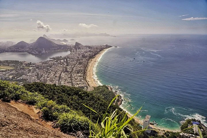 Expansive view of Rio de Janeiro coastline, city, and mountains from a high vantage point.