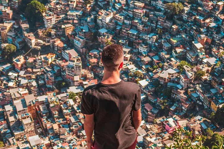 Personne regardant d'en haut les habitations denses d'une favela à flanc de colline.